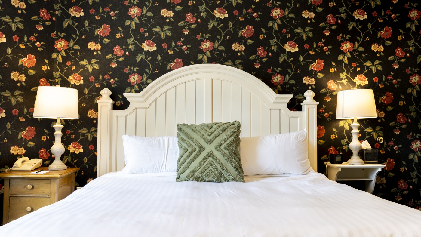 Luxuriously appointed guest room at the Inn on Broadway featuring plush bedding and dark wallpaper with flora designs