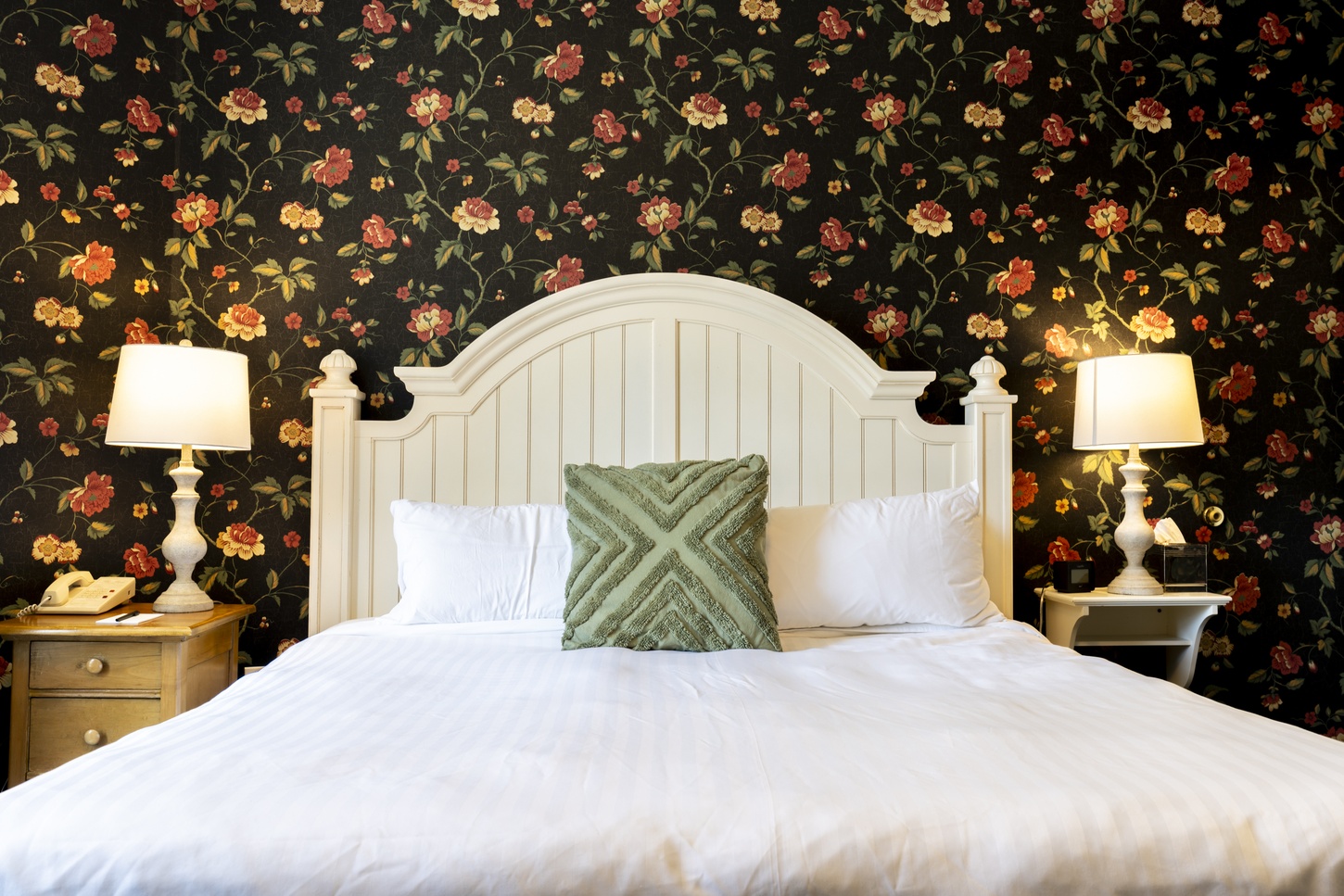 Luxuriously appointed guest room at the Inn on Broadway featuring plush bedding and dark wallpaper with flora designs